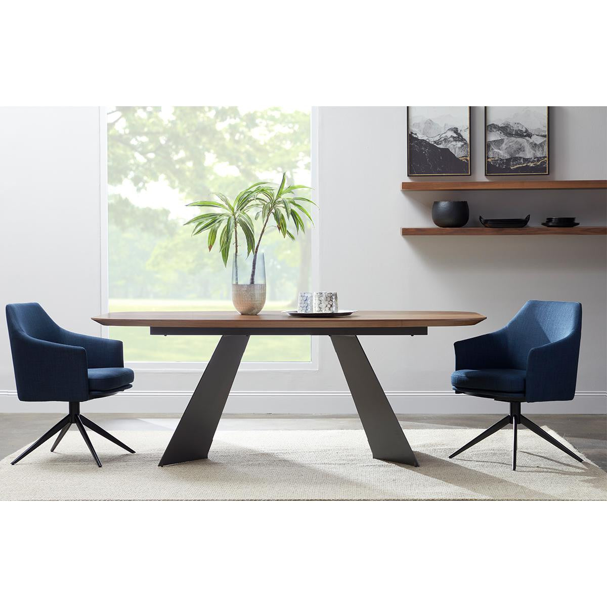 Modern wood dining table with black trapezoid legs paired with two blue swivel chairs on a light rug in a bright, contemporary dining room