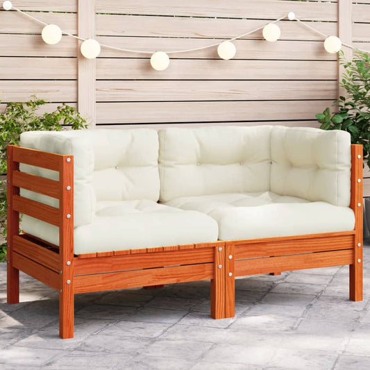 A stylish, modern wooden outdoor love seat with thick, off-white cushions, sitting on a patio. The love seat is made of acacia wood with a rich reddish-brown finish.